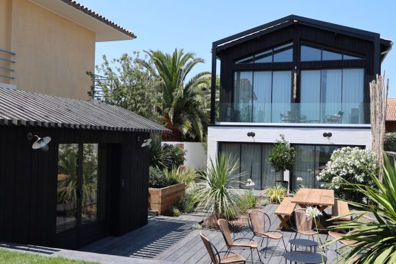 Façade contemporaine noire et blanche donnant sur une terrasse paysagée.
