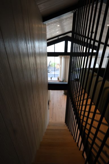 Escalier contemporain avec claustra métallique noir donnant sur le séjour.