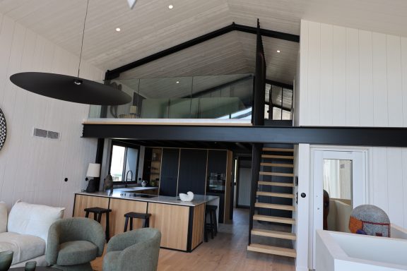 Vue d’ensemble de la cuisine et de la mezzanine reliées par un escalier en bois.