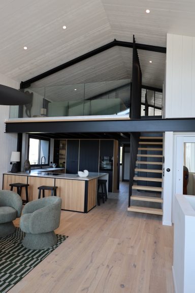 Vue d’ensemble de la cuisine et de la mezzanine reliées par un escalier en bois.