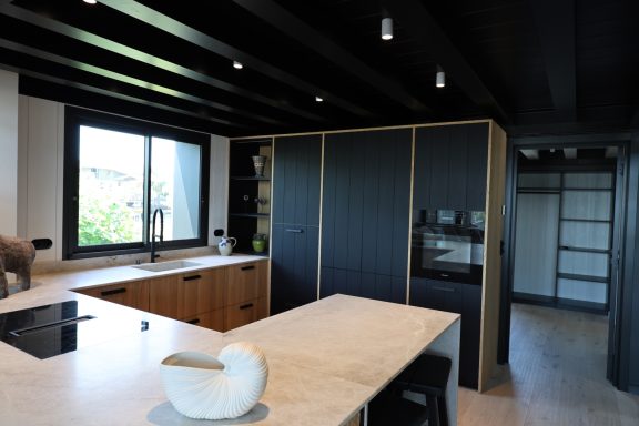 Cuisine contemporaine en bois et bleu profond avec îlot central en pierre claire.