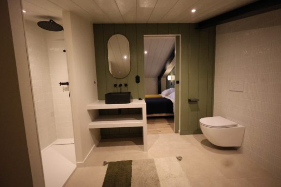 Salle de bains avec meuble vasque noir, mur vert et baignoire.