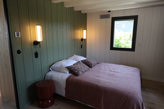 Chambre aux murs vert sauge avec appliques murales dans une maison au Cap Ferret.
