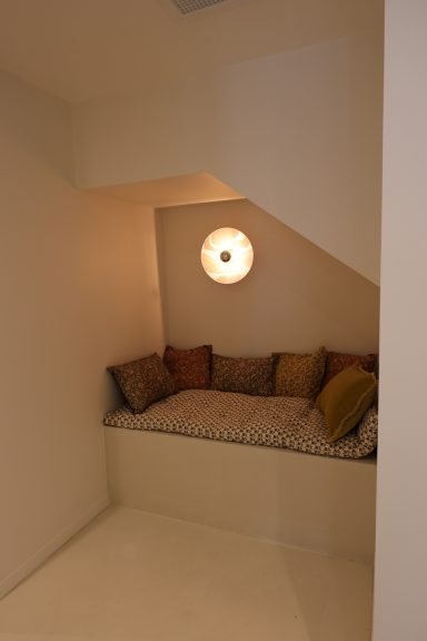 Banquette intégrée sous l’escalier avec coussins aux motifs chaleureux.