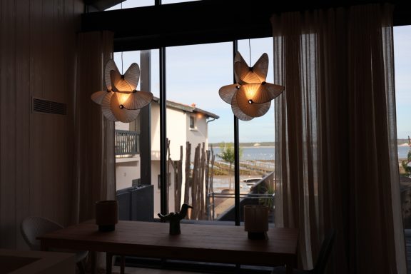 Suspensions sculpturales devant une baie vitrée avec vue sur le Bassin d’Arcachon.