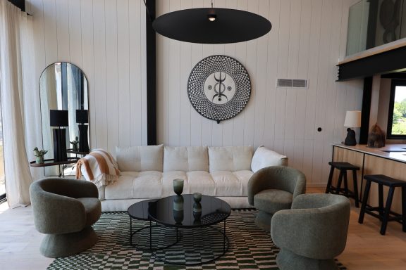 Salon chaleureux avec canapé clair, fauteuils arrondis et table basse noire