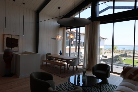 Salon et salle à manger ouverts sur les grandes baies vitrées face au Bassin.