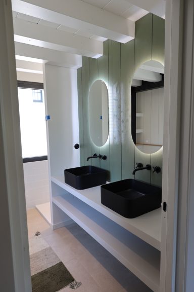 Double vasque noire avec miroirs lumineux dans la salle de bains.