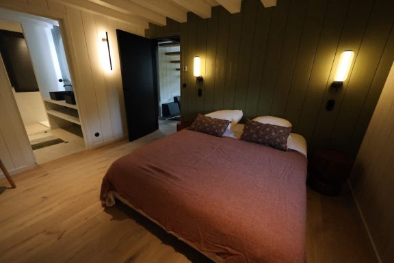 Chambre parentale aux murs vert profond avec appliques murales.