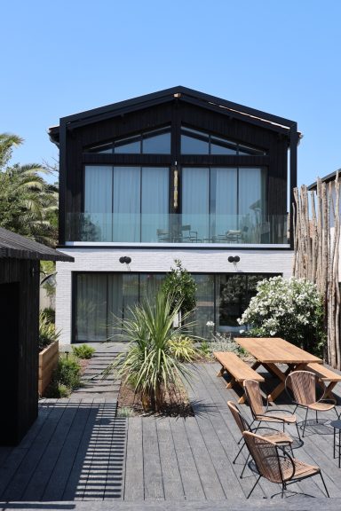 Maison contemporaine en première ligne avec façade vitrée et terrasse en bois.