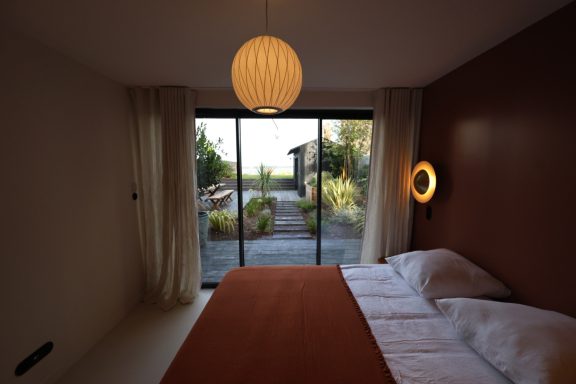 Chambre terracotta avec grande baie vitrée donnant sur le jardin.