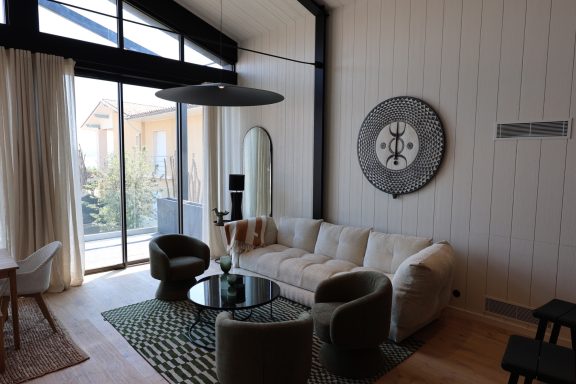 Aménagement du salon face aux grandes baies vitrées de la maison.