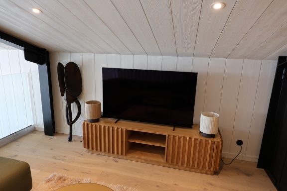Meuble de télévision en bois aux lignes arrondies dans le salon secondaire.