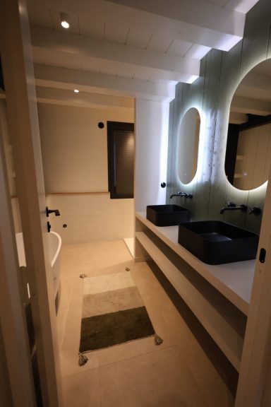 Salle de bains avec baignoire et double vasque noire sur mesure.